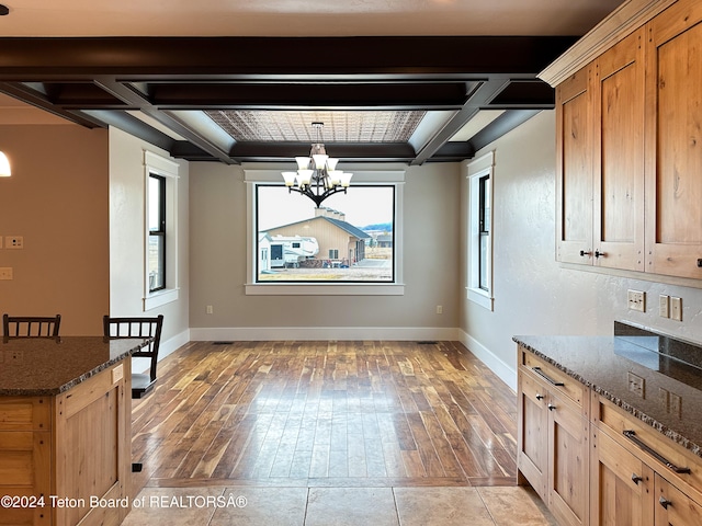 unfurnished dining area with an inviting chandelier, beamed ceiling, coffered ceiling, and light wood-type flooring