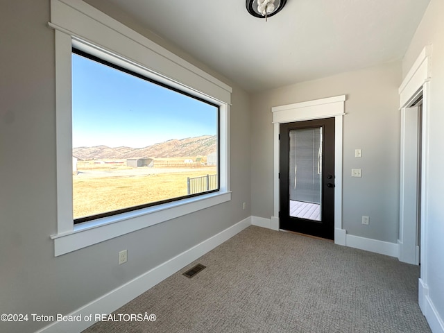 entrance foyer with a mountain view, carpet flooring, and plenty of natural light