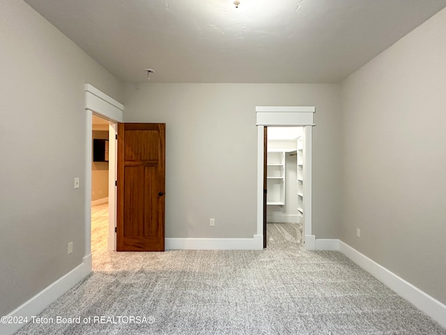 unfurnished bedroom with carpet floors, a spacious closet, and a closet