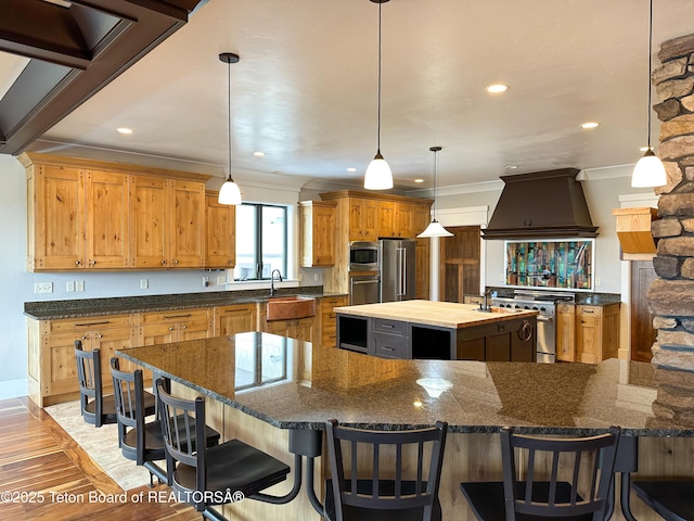 81 Twin Cliffs Rd, Afton, WY 83110 - kitchen featuring custom exhaust hood, premium appliances, a large island, crown molding, and light wood-type flooring