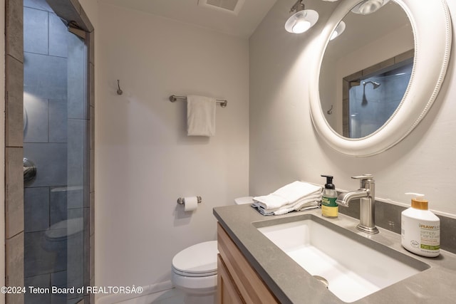 bathroom featuring a tile shower, vanity, and toilet