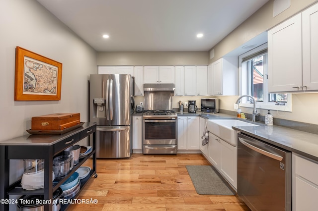 kitchen with sink, white cabinets, stainless steel appliances, and light hardwood / wood-style floors