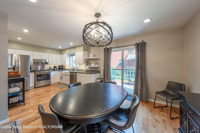 dining area with light wood-type flooring, an inviting chandelier, and sink