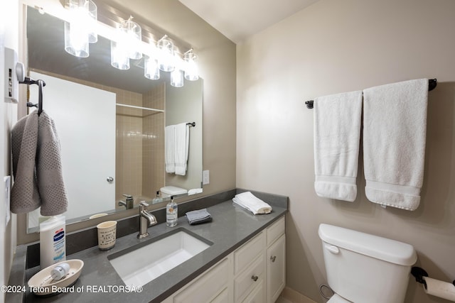 bathroom with vanity, toilet, and tiled shower