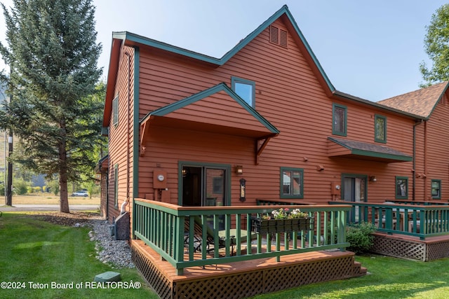 rear view of property with a wooden deck and a yard