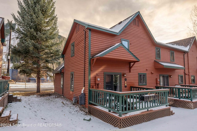 snow covered rear of property with a wooden deck