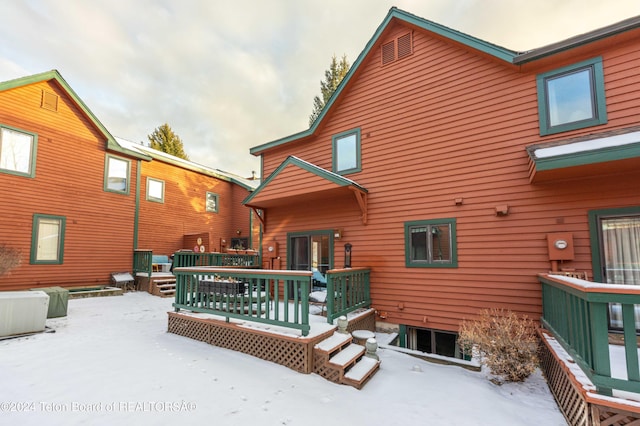 snow covered back of property featuring a wooden deck