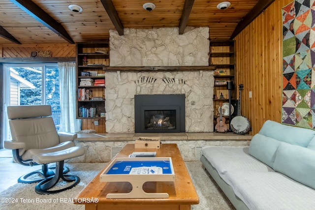 living room featuring beam ceiling, wooden walls, a fireplace, and wood ceiling