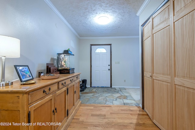 entrance foyer with ornamental molding, a textured ceiling, and light hardwood / wood-style flooring