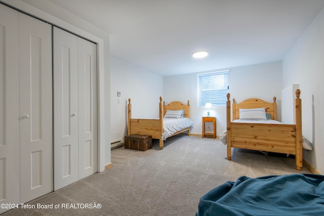 bedroom with a closet, light carpet, and a baseboard heating unit