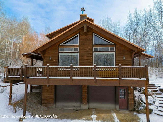 snow covered back of property with a wooden deck