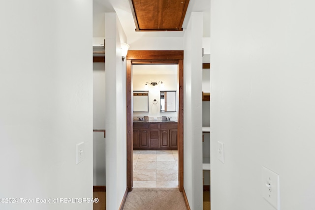 corridor with sink and light colored carpet