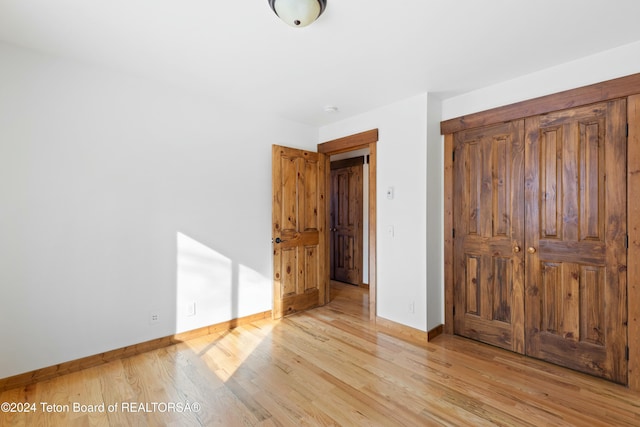 unfurnished bedroom with light wood-type flooring and a closet