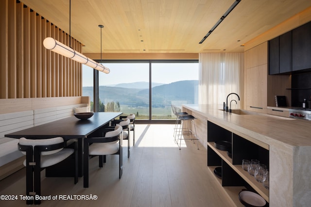 dining room with wood ceiling, sink, a mountain view, and floor to ceiling windows