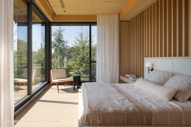 bedroom featuring wooden ceiling, a wall of windows, and multiple windows