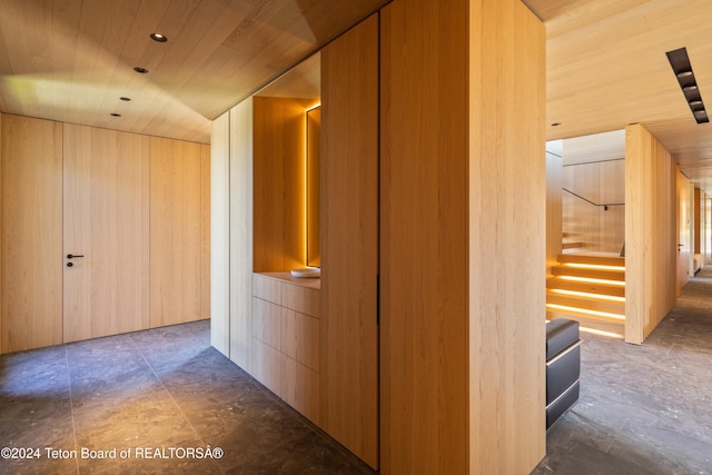 hallway featuring wooden ceiling and wood walls