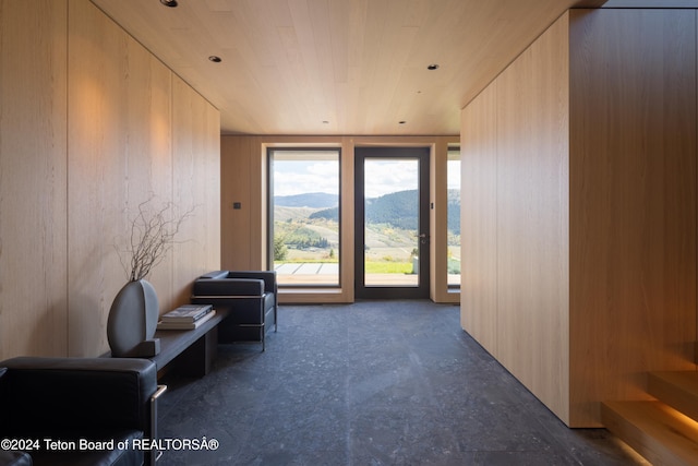 living area with a healthy amount of sunlight, wood ceiling, wooden walls, and a mountain view