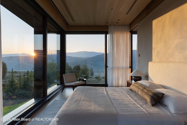 unfurnished bedroom with a mountain view, wooden ceiling, multiple windows, and hardwood / wood-style flooring