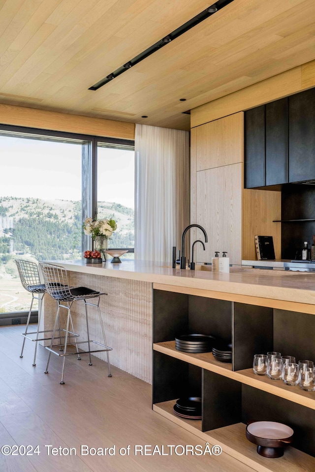 kitchen with wood ceiling, wooden walls, a mountain view, and light hardwood / wood-style flooring