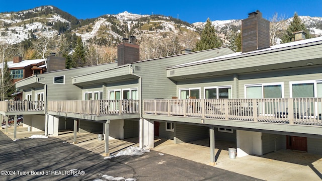 snow covered back of property with a deck with mountain view