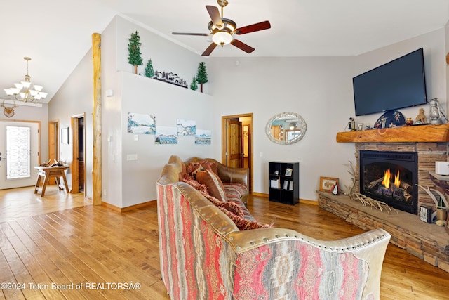 living room featuring a fireplace, ceiling fan with notable chandelier, hardwood / wood-style flooring, and high vaulted ceiling