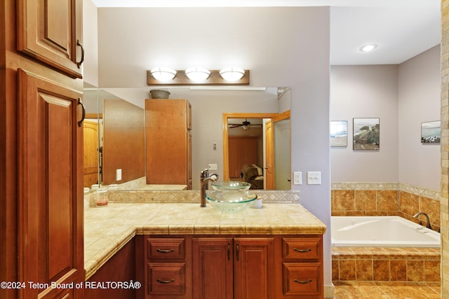 bathroom with a relaxing tiled tub, vanity, and ceiling fan