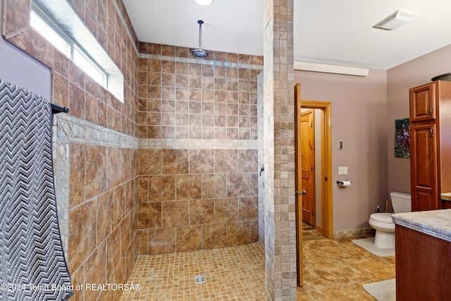 bathroom with tile patterned floors, toilet, vanity, and tiled shower