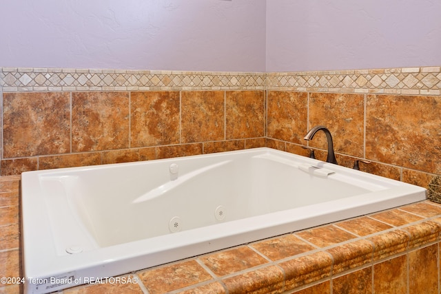 bathroom featuring a relaxing tiled tub and tile walls