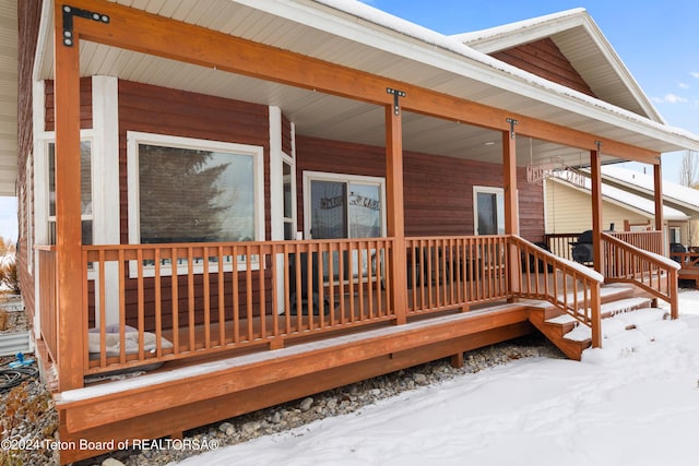 snow covered deck with a porch