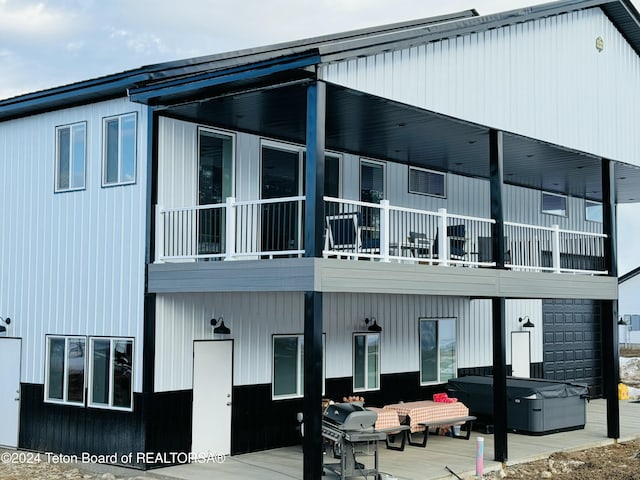 back of house featuring a balcony and a hot tub