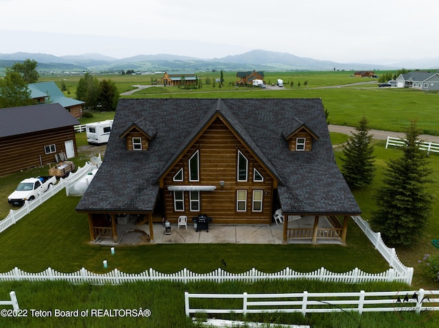 back of property with a mountain view, a patio, and a lawn