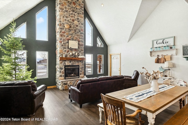 dining area featuring hardwood / wood-style floors, high vaulted ceiling, a stone fireplace, and a wealth of natural light