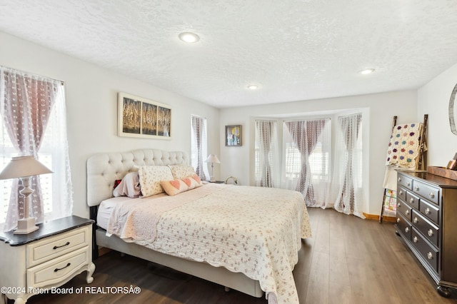 bedroom featuring multiple windows, dark wood-type flooring, and a textured ceiling