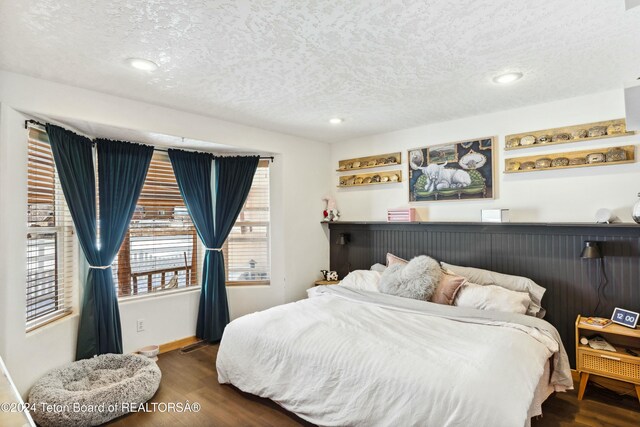 bedroom with a textured ceiling and dark wood-type flooring