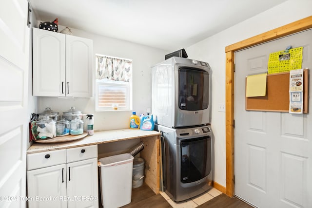 laundry room with dark hardwood / wood-style floors, cabinets, and stacked washer / dryer