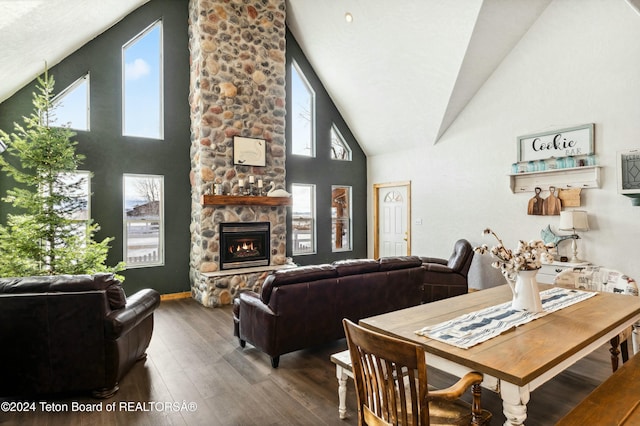 dining area featuring plenty of natural light, wood-type flooring, a fireplace, and high vaulted ceiling