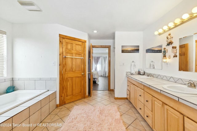 bathroom with tile patterned flooring, vanity, and a relaxing tiled tub