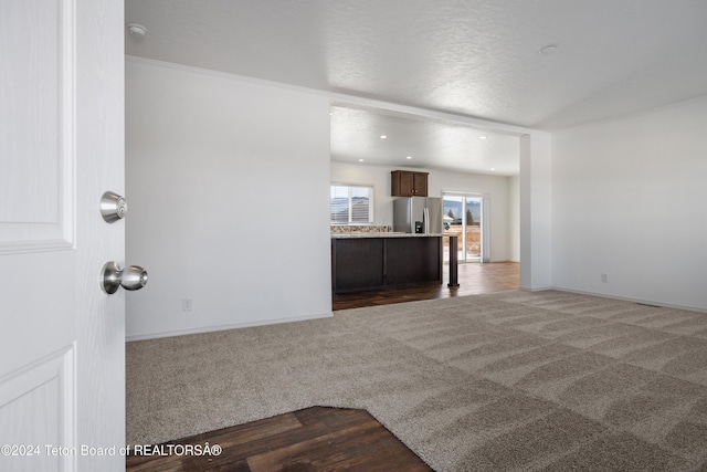 unfurnished living room with dark carpet and a textured ceiling