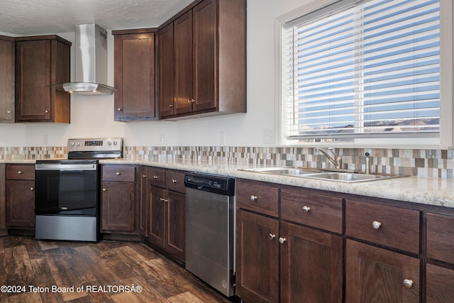 kitchen with wall chimney exhaust hood, a healthy amount of sunlight, sink, and appliances with stainless steel finishes