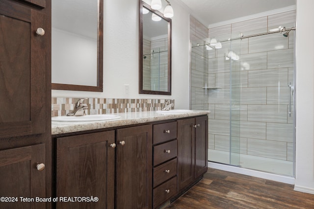 bathroom featuring backsplash, hardwood / wood-style flooring, a shower with door, vanity, and ornamental molding