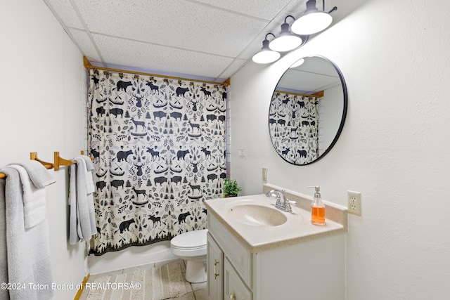 bathroom featuring tile patterned floors, a drop ceiling, toilet, and vanity