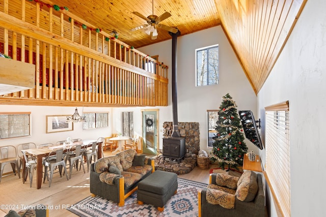 living room featuring a towering ceiling, ceiling fan, hardwood / wood-style flooring, wooden ceiling, and a wood stove