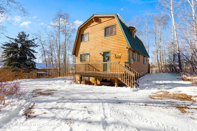 snow covered rear of property featuring a deck