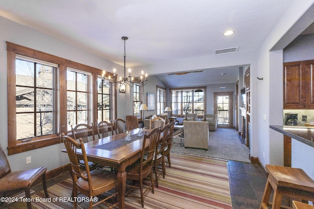 dining room featuring carpet, a healthy amount of sunlight, and an inviting chandelier