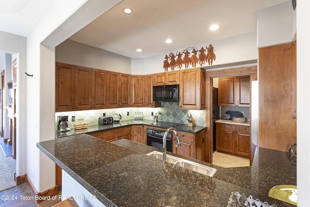 kitchen featuring dark stone counters, black appliances, sink, light hardwood / wood-style floors, and kitchen peninsula