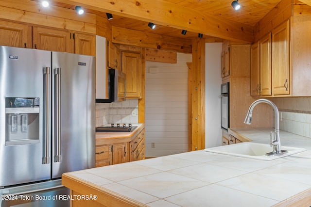 kitchen featuring tile countertops, oven, sink, high end fridge, and gas cooktop