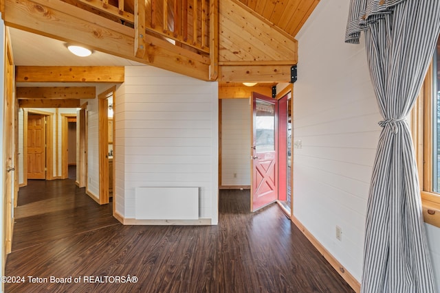 spare room featuring lofted ceiling, dark hardwood / wood-style floors, and wooden walls