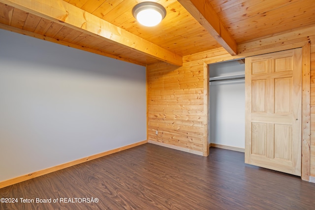 unfurnished bedroom with wooden walls, dark hardwood / wood-style flooring, and beamed ceiling