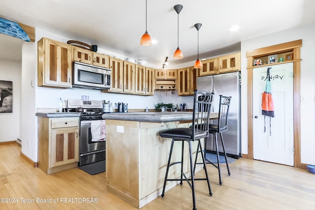 kitchen featuring pendant lighting, a kitchen bar, stainless steel appliances, and light hardwood / wood-style flooring