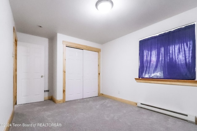 unfurnished bedroom featuring carpet flooring, a closet, and baseboard heating